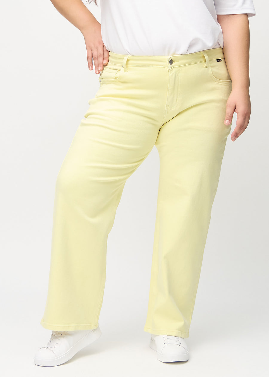 Lysegule loose jeans, modelnavn Lemonades, som er løstsiddende med masser af vidde i benene på en plus-size model, set forfra.
