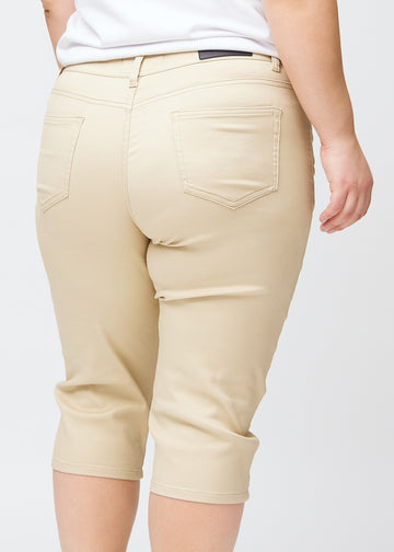 Tæt billede af bagdelen på en plus-size model i beige slim capris – detaljefokus på lommer og syninger.