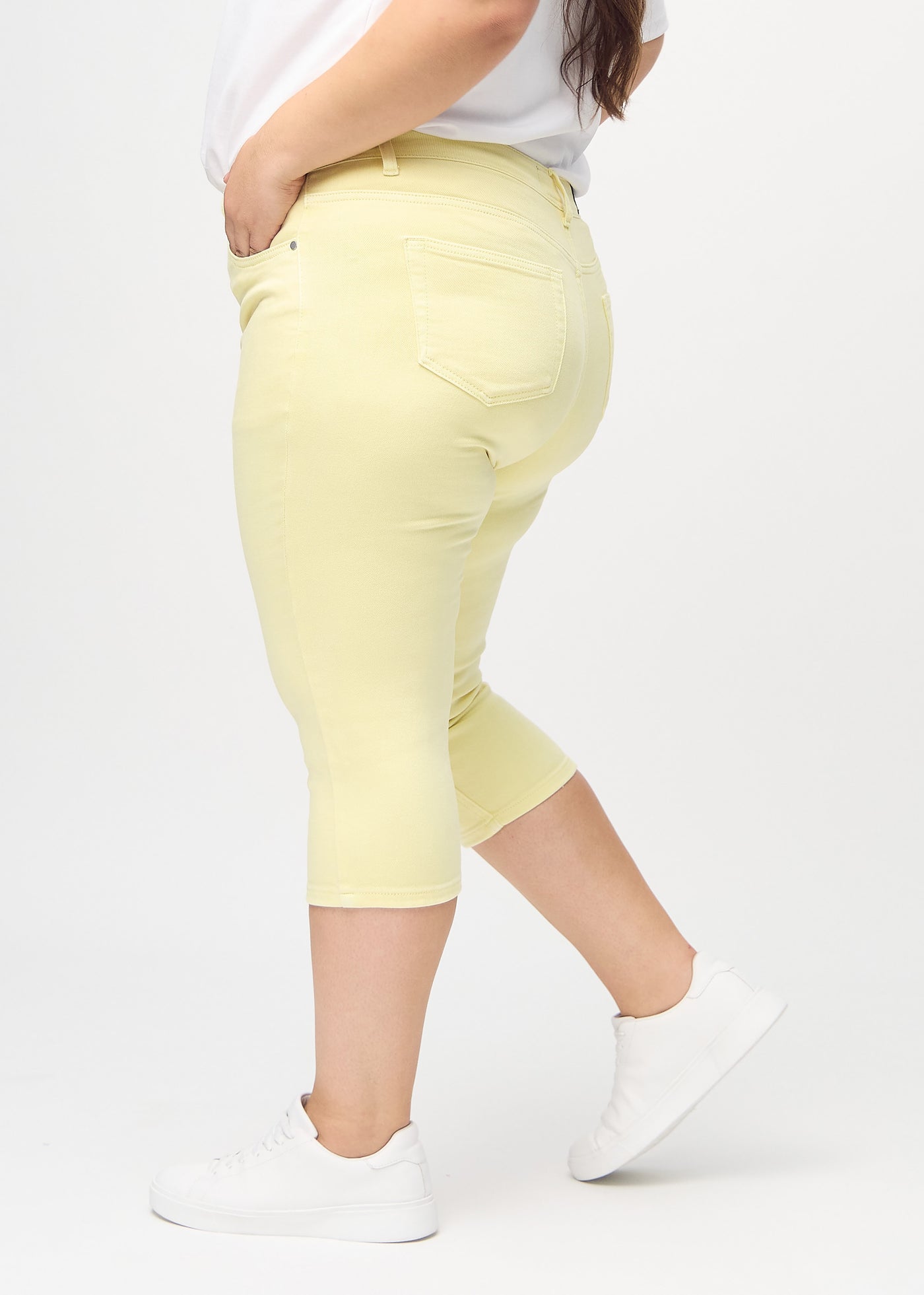 Lysegule skinny capris set fra siden på en plus-size model.