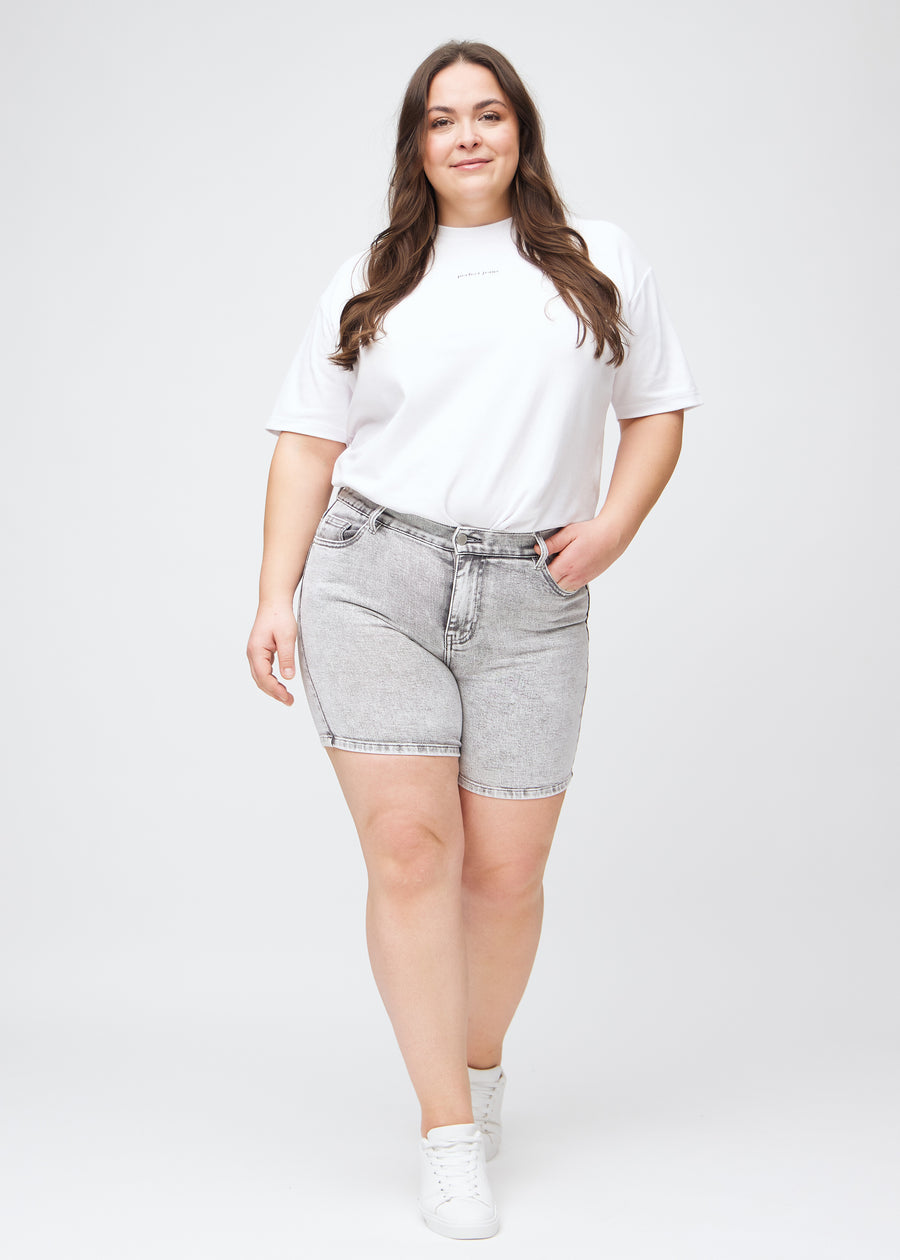 Fuldt billede af en plus-size model i lysegrå denim skinny short shorts.