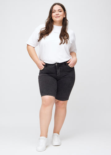 Fuldt billede af en plus-size model i mørkegrå denim skinny middle shorts.