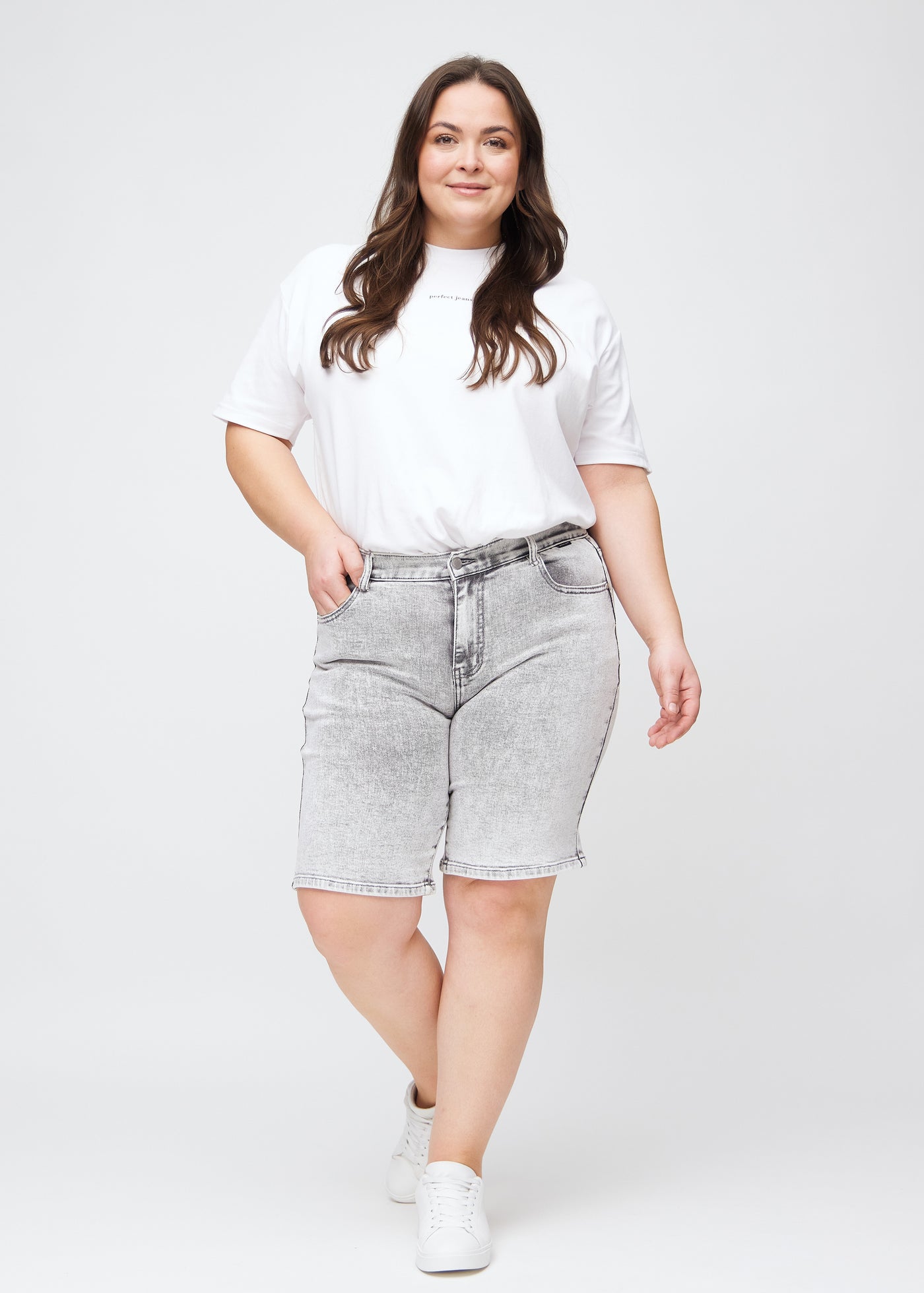 Fuldt billede af en plus-size model i lysegrå denim regular middle shorts.