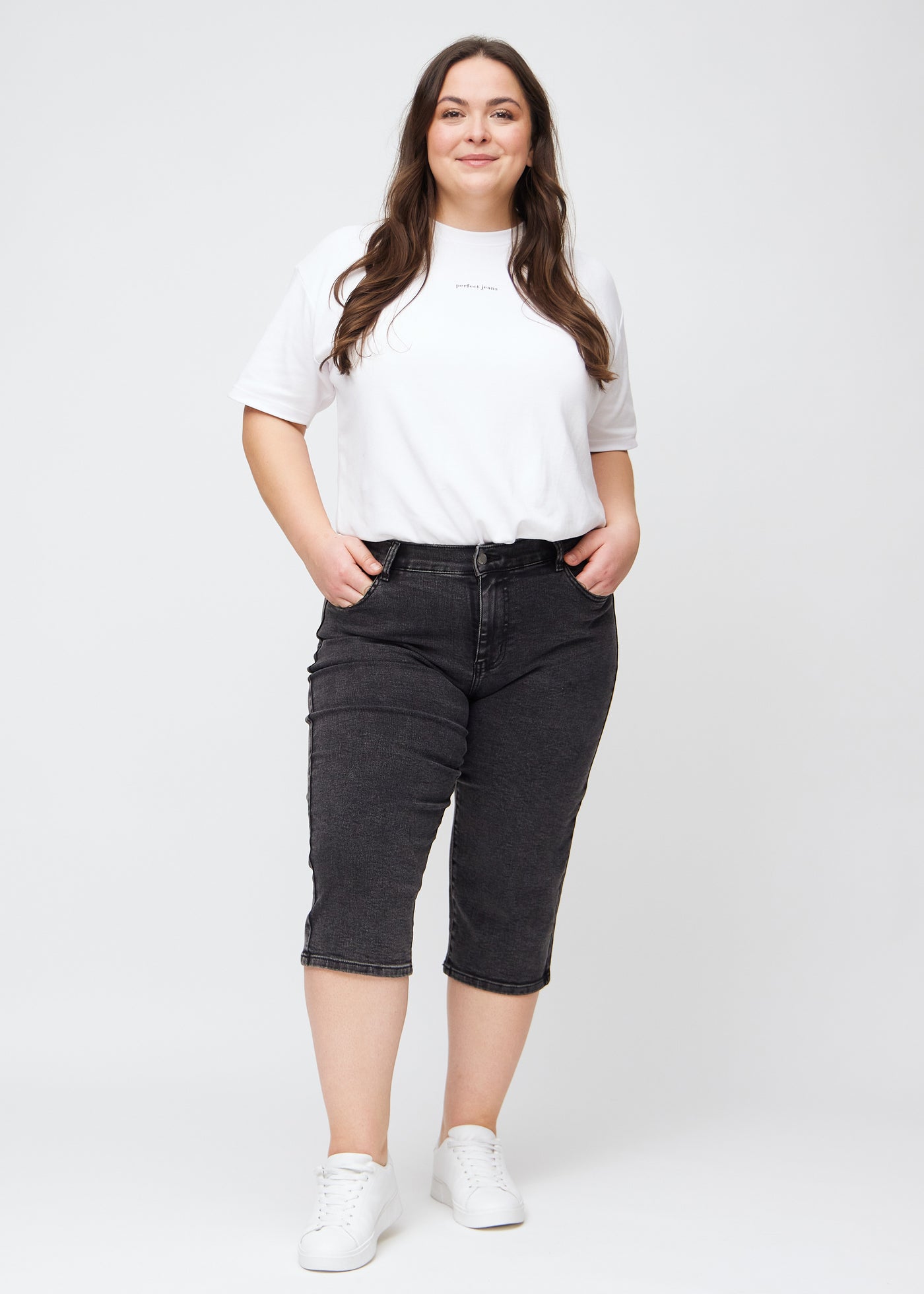 Fuldt billede af en plus-size model i mørkegrå denim regular capris.