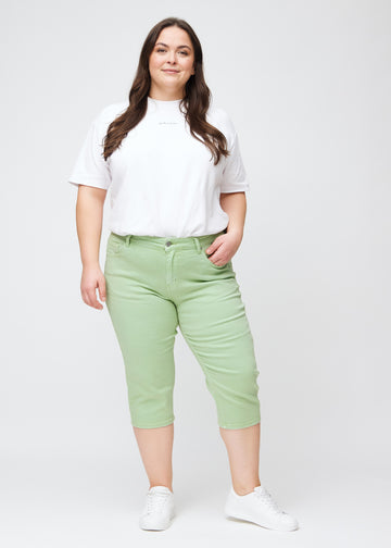 Fuldt billede af plus-size model i lysegrønne slim capris.