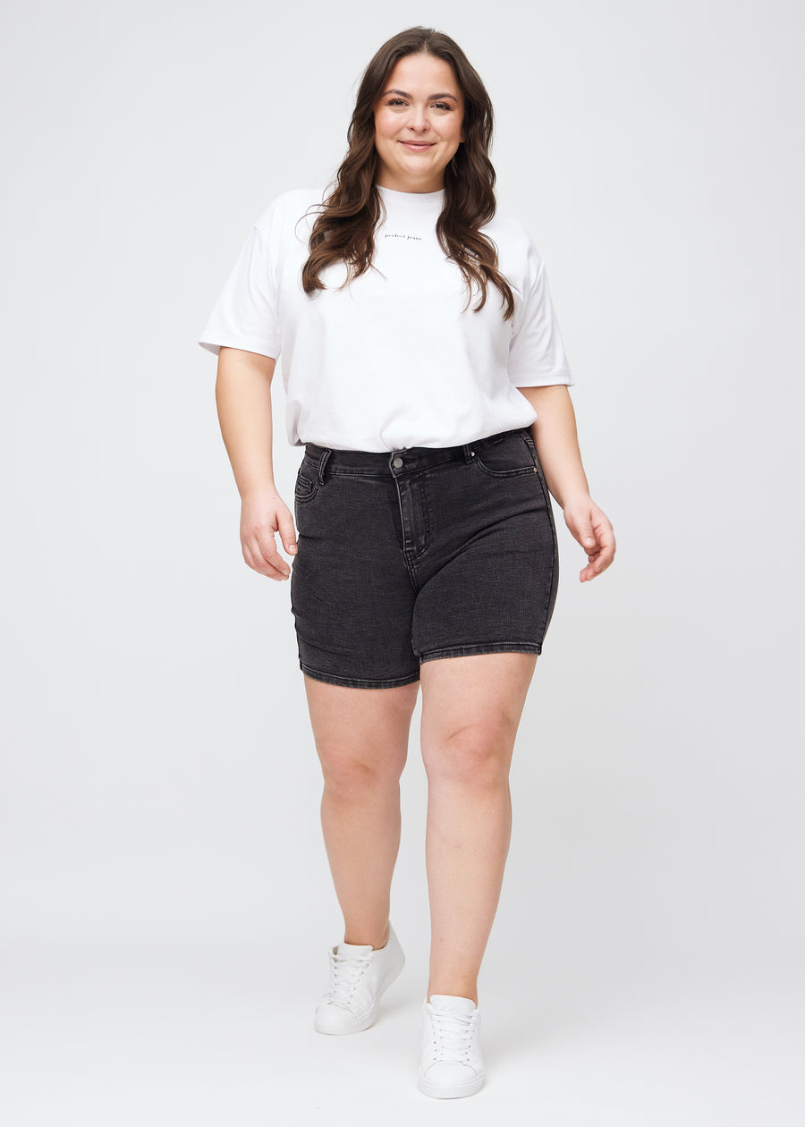 Plus-size model går ind i billedet, strækker i sine shorts, viser dem frem ved at dreje rundt, og forlader derefter billedet.