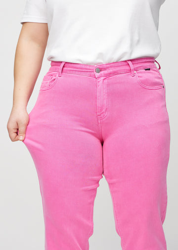 Plus-size model strækker jeansene ved låret for at vise stretch.