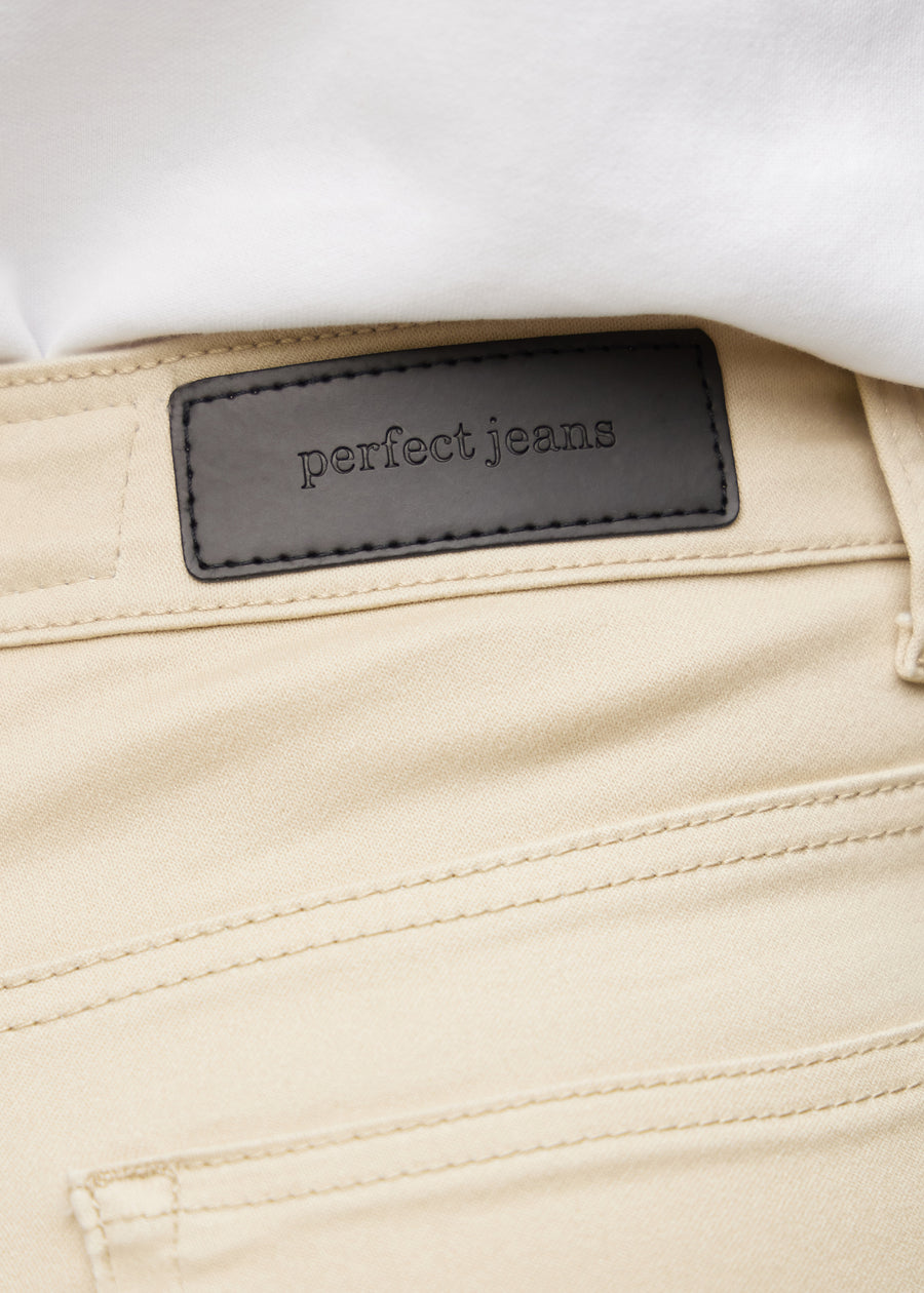Close-up of beige jeans material with the Perfect Jeans leather patch at the back of the waistband.