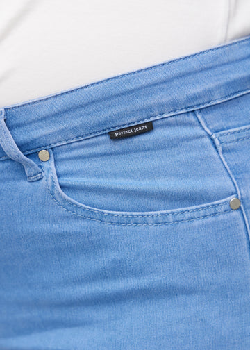 Nærbillede af blåt jeansmateriale med Perfect Jeans logoetiket ved forlommekanten, på en plus-size model.
