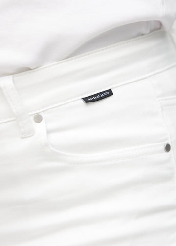 Nærbillede af hvidt jeansmateriale med Perfect Jeans logoetiket ved forlommekanten, på en plus-size model.
