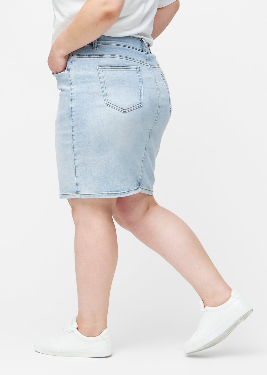 Lyseblå, tætsiddende og knælang denimnederdel set fra siden på plus-size model.
