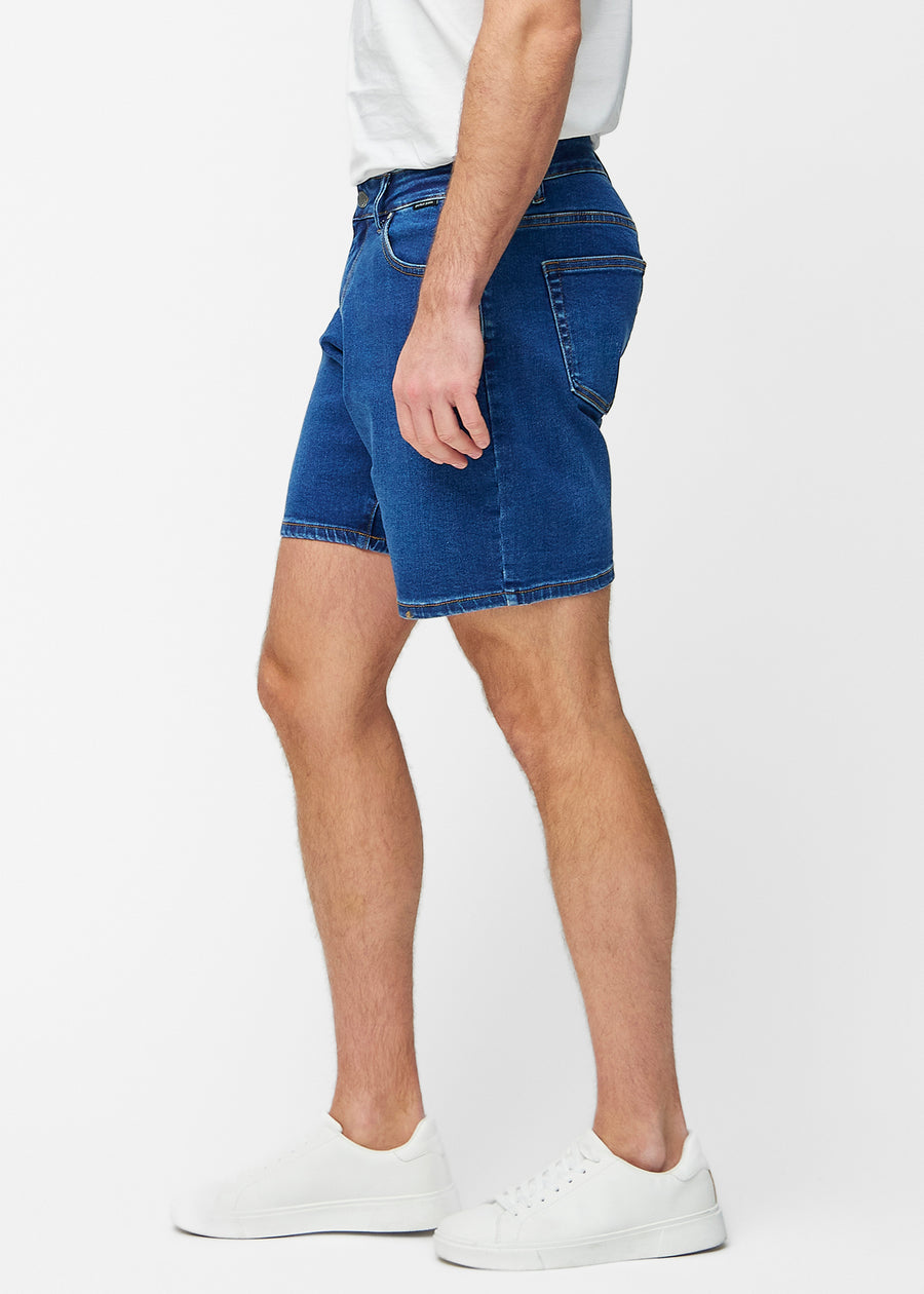 Dark blue denim shorts for men in the colour Oceans with a regular fit seen from the side on a model.