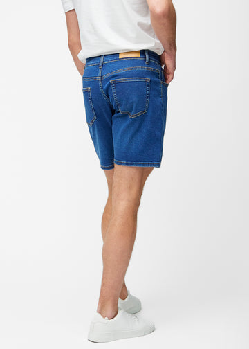 Dark blue denim shorts for men in the colour Oceans with a regular fit seen from the side on a model.