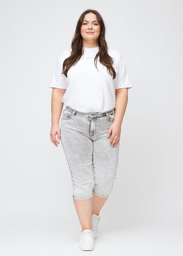 Full image of a plus-size model in light grey denim regular capris.