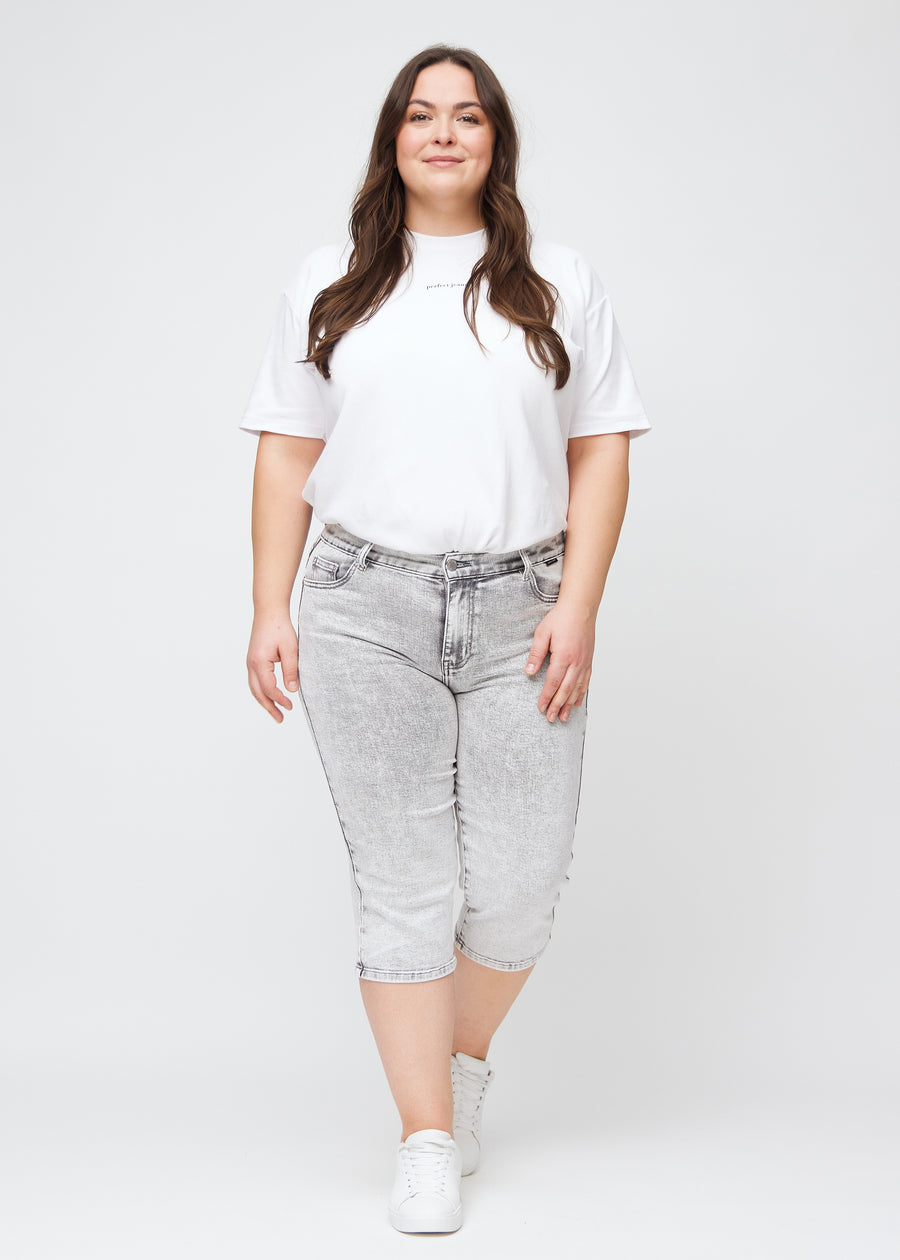 Full image of a plus-size model in light grey denim regular capris.