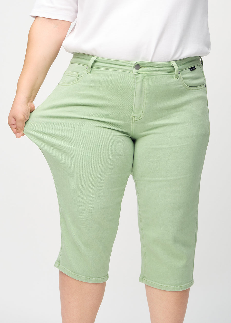 The plus-size model stretches the capris at the thigh to show the stretch.