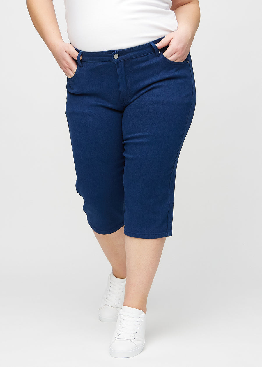 Dark blue regular capris, model name Royals, with a straight fit through the leg and ending just below the knee on a plus-size model, seen from the front.