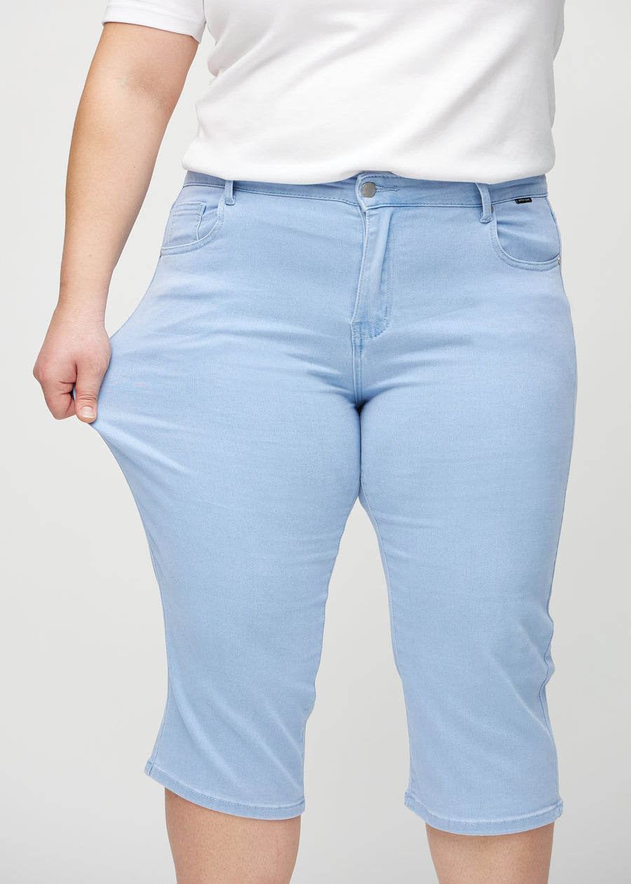 The plus-size model stretches the capris at the thigh to show the stretch.