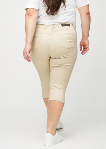 Beige skinny capris seen from the back on a plus-size model, so the entire product is visible.