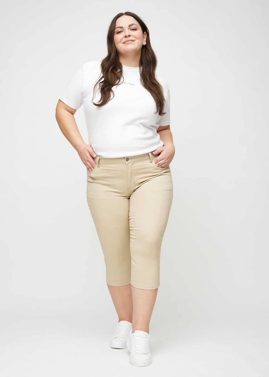 Full image of a plus-size model in beige skinny capris.