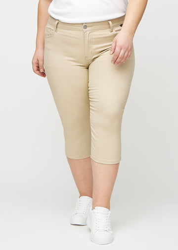 Beige skinny capris, model name Gazelles, which fit close to the leg and end just below the knee on a plus-size model, seen from the front.