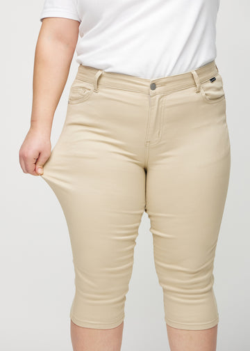 The plus-size model stretches the capris at the thigh to show the stretch.