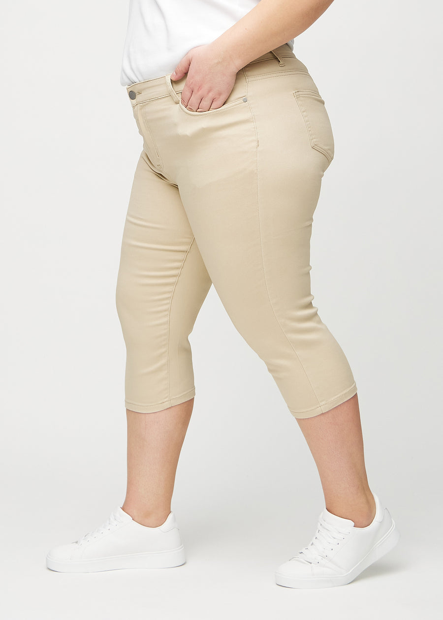 Beige skinny capris seen from the side on a plus-size model.