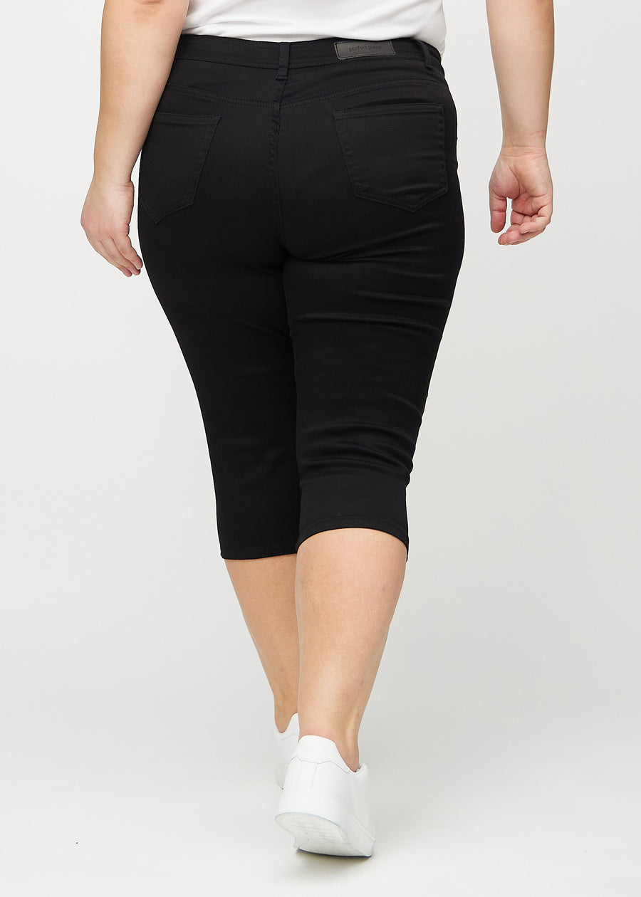 Skinny capris for women in black fabric, color Ravens. Back view on a plus-size model, showing the fit and back pockets.