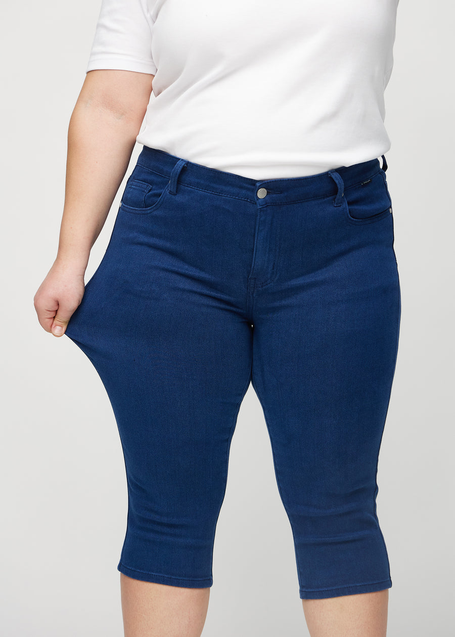 The plus-size model stretches the capris at the thigh to show the stretch.