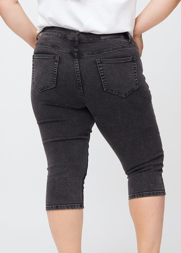 Skinny capris for women in dark grey denim, color Shadows. Close-up from behind on a plus-size model, highlighting pockets and stitching.
