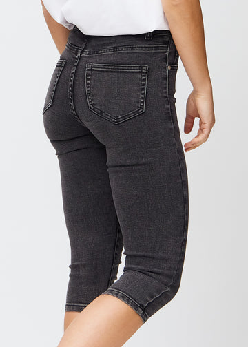 Skinny capris for women in dark grey denim, color Shadows. Close-up from behind on a model, highlighting pockets and stitching.