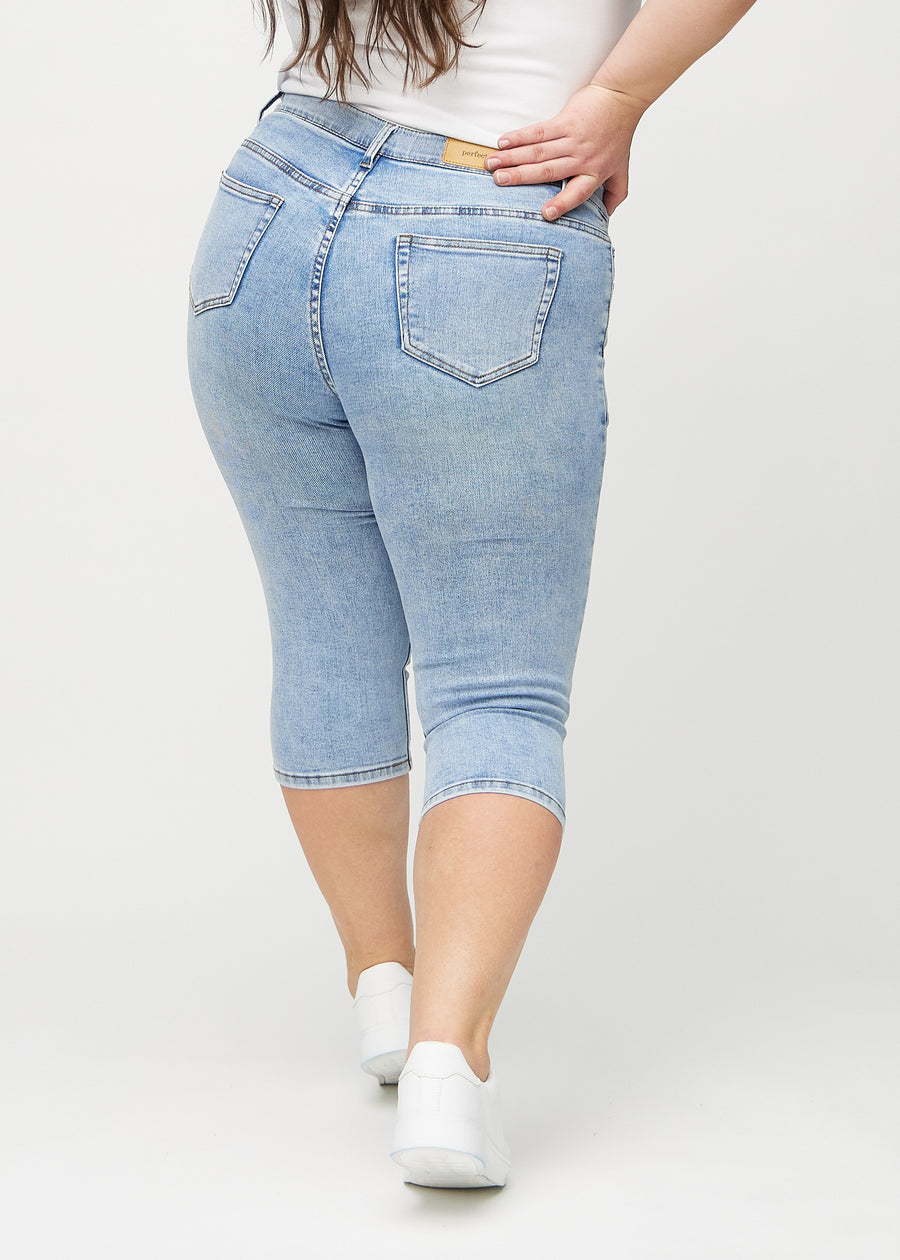 Light denim skinny capris viewed from the back on a plus-size model, so the entire product can be seen.
