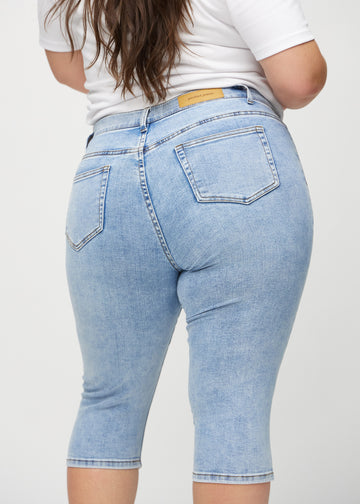 Light denim skinny capris viewed from the back close up on a plus-size model to show details.