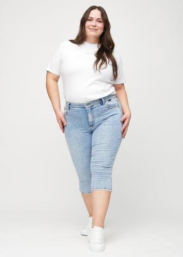 Full image of a plus-size model in light denim skinny capris.