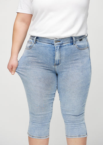 The plus-size model stretches the capris at the thigh to show the stretch.