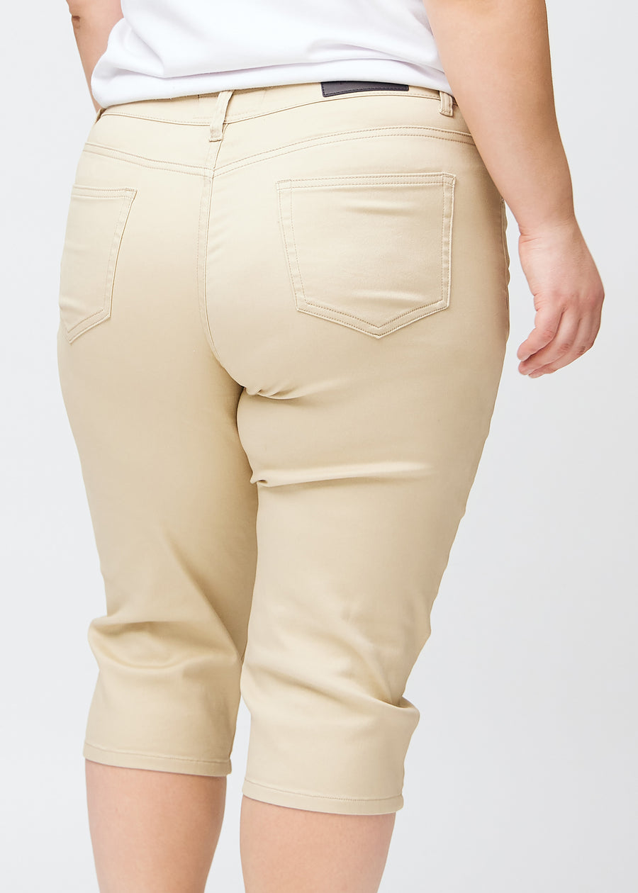 Close-up image of the back on a plus-size model wearing beige slim capris, detailed focus on pockets and stitching.