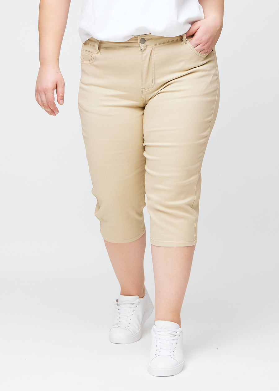 Beige slim capris, colour Gazelles, with a close-fitting fit and length just below the knee, seen from the front on a plus-size model.