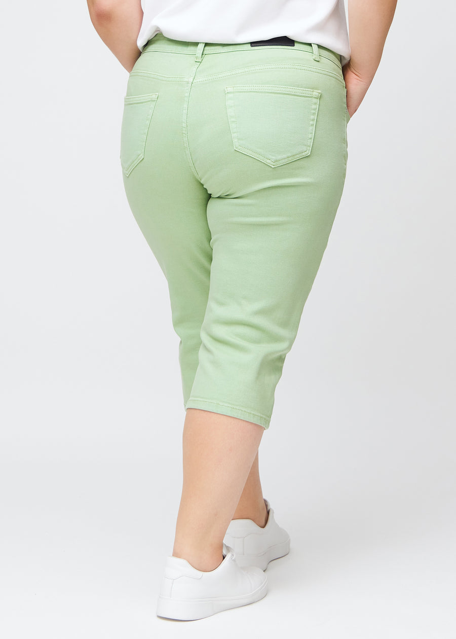 Slim capris for women in pastel light green jeans fabric, color Mints. Back view on a plus-size model, showing the fit, length and back pockets.