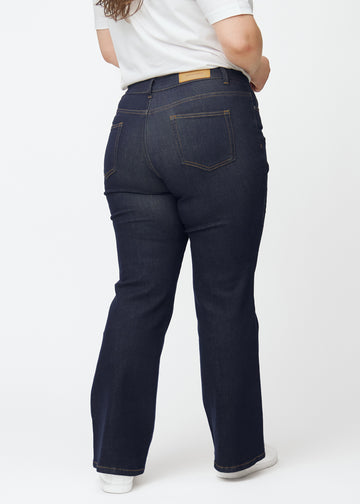 Deep dark blue denim jeans for women in the color Midnights seen from the back on a plus-size model.