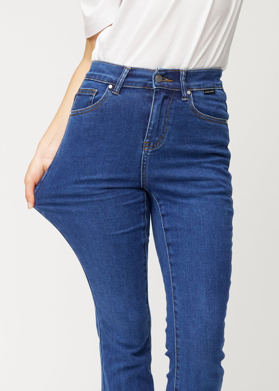 Dark blue mid-rise bootcut jeans in Oceans. A model stretches the jeans at the thigh to show the fabric&