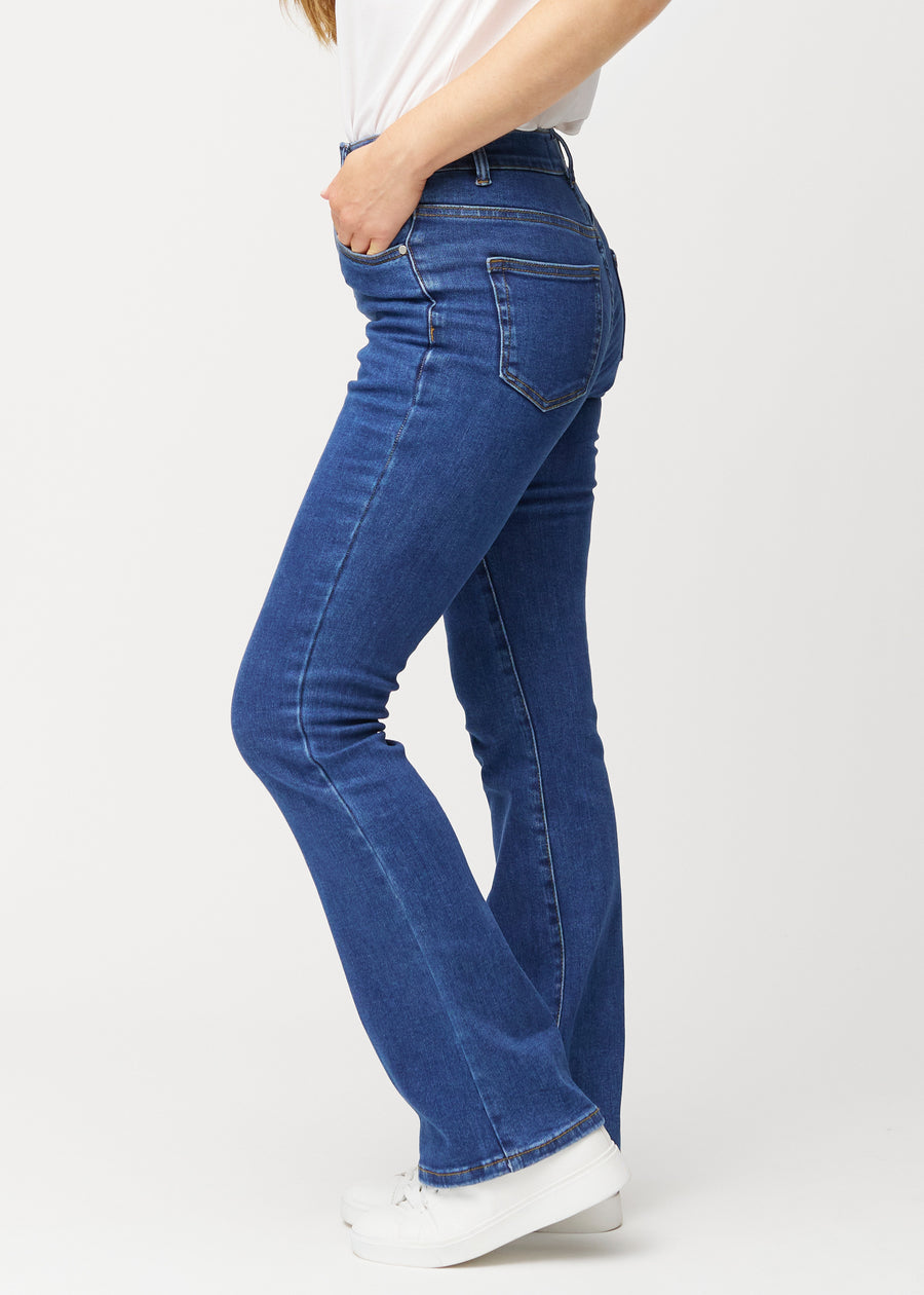 Dark blue mid-rise bootcut jeans in Oceans. Side view on a model.