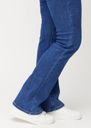 Dark blue mid-rise bootcut jeans in Oceans. Close-up of the ankle area on a model, showing the subtle bootcut flare.