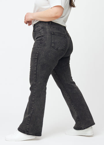 Dark grey mid-rise bootcut jeans in Shadows. Side view on a plus-size model.