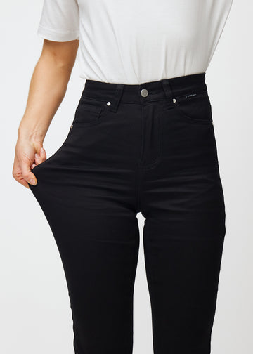 The model stretches the jeans at the thigh to show the stretch.