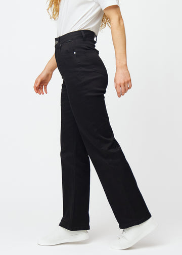 Black high-waisted jeans, which are fitted at the waist and have a loose fit with width down the leg, shown from the side on a model.