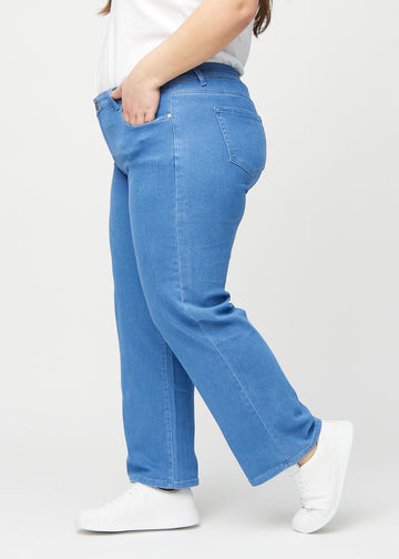 Blue loose jeans seen from the side on a plus-size model.