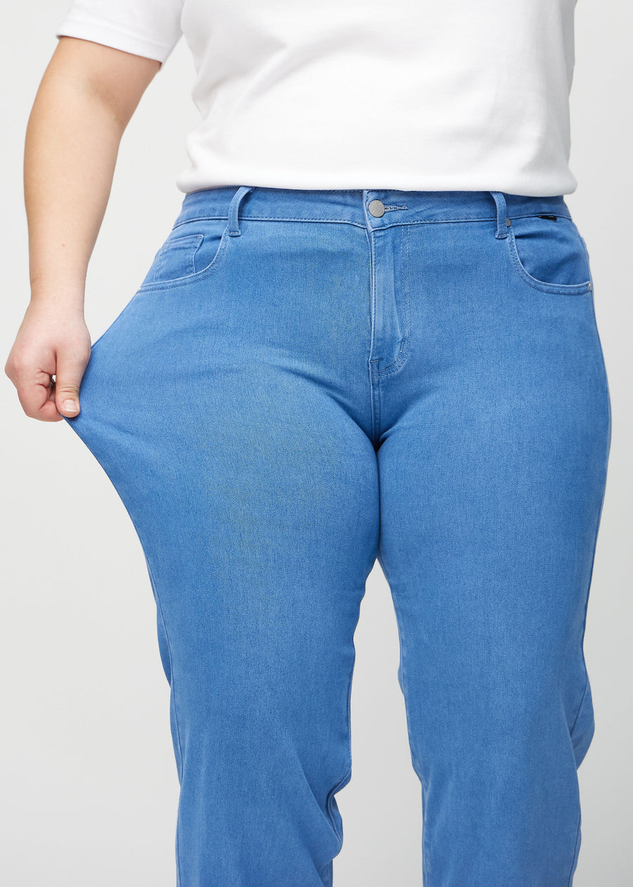 The plus-size model stretches the jeans at the thigh to show the stretch.