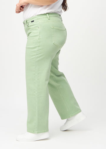 Light green loose jeans seen from the side on a plus-size model.
