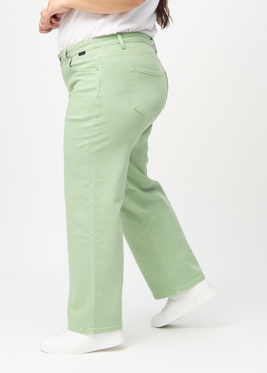 Light green loose jeans seen from the side on a plus-size model.
