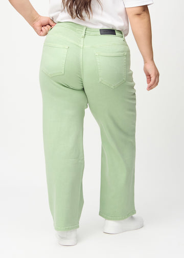 Light green loose jeans seen from the back on a plus-size model, so the entire product can be seen.
