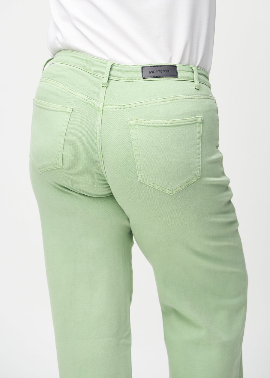 Light green loose jeans seen from the back close up on a plus-size model to show details.
